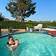Noelyne participe au concours pour gagner de l'argent avec cette photo : woman, child, swimming_pool, water, outdoor, sunny, blue_sky, tree, hedge, lounge_chair, plant_pots, summer, recreation, leisure, happy, fun, family, vacation, nature, relaxation