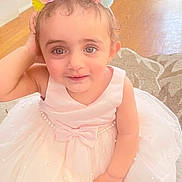 Engy is registered to the contest to win money with this photo: toddler, child, birthday, crown, flower_crown, dress, pink_dress, pearl, bow, indoor, floor, rug, cute, smile, portrait, baby, person, celebration, happy, young_child