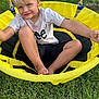 child, blond_hair, blue_eyes, swing, yellow, outdoor, grass, smile, happy, playful, casual_clothing, shorts, tshirt, barefoot, summer, daylight, park, fun, relaxing, portrait