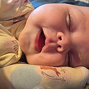 Ainsley is registered to the contest to win money with this photo: baby, sleeping, face, close_up, smile, infant, soft_lighting, peaceful, cozy, fabric, patterned_clothing, skin, child, cute, resting, portrait, newborn, warm_colors, eyelashes, nostrils