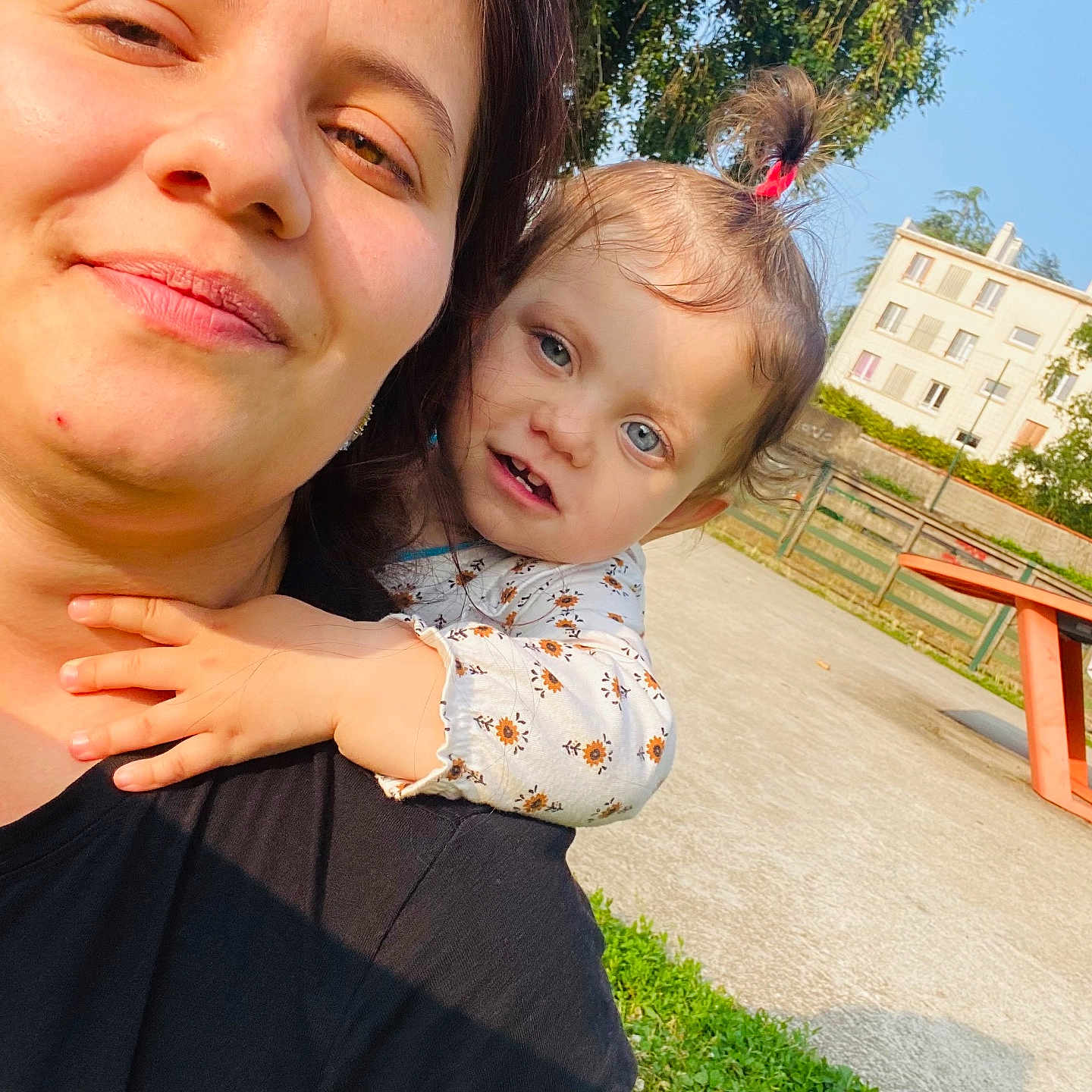 Mirela Marin participe au concours pour gagner de l'argent avec cette photo : building, casual, child, clothing, daytime, earring, face, fence, greenery, hair, hand, nature, outdoor, person, playground, sky, smile, sunlight, toddler, woman