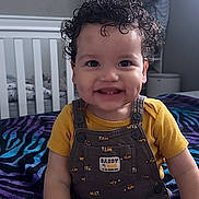 Zandyel joined the competition — help win amazing prizes! toddler, child, smiling, curly_hair, dimples, yellow_shirt, overalls, bedroom, blanket, zebra_pattern, furniture, bed, clothing, cute, happy, indoor, person, sitting, young_child, playful