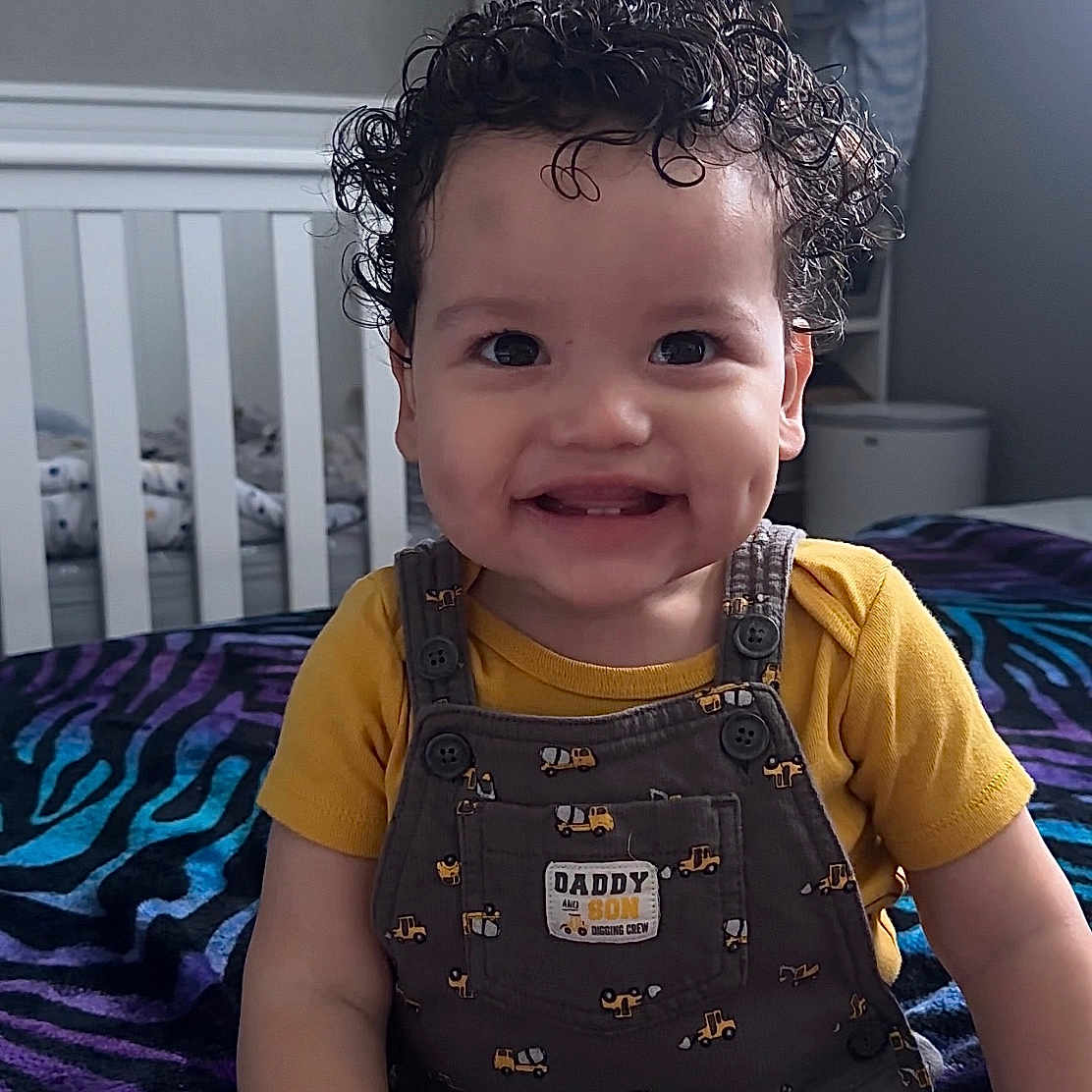 Zandyel joined the competition — help win amazing prizes! bed, bedroom, blanket, child, clothing, curly_hair, cute, dimples, furniture, happy, indoor, overalls, person, playful, sitting, smiling, toddler, yellow_shirt, young_child, zebra_pattern