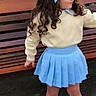 child, girl, toddler, portrait, outdoor, park, bench, fashion, blue_bow, curly_hair, skirt, sweater, sneakers, standing, posing, face, hair, playground, palm_tree, daylight
