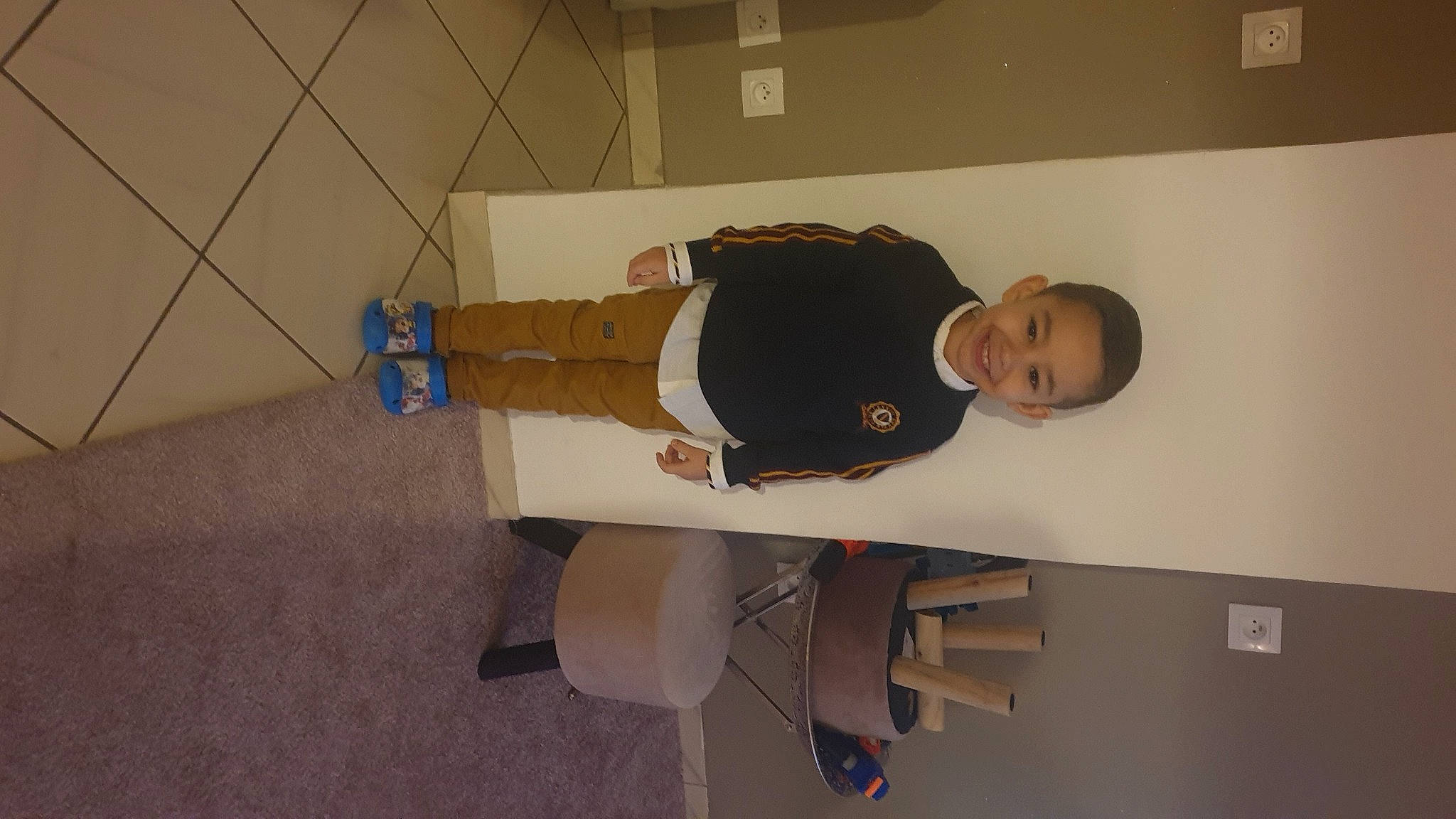 Adem a rejoint le concours — aidez-le/la à gagner de superbes lots ! child, collar, elbow, flooring, hardwood, joy, khaki_pants, paper_product, person, room, walking_shoe, wood, wrist