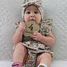 baby, infant, child, floral_outfit, headband, wooden_sign, 4_months, cute, sitting, blanket, texture, footwear, pink_shoes, playful, curious, portrait, indoors, hands, face, expression