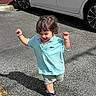 Victor is registered to the contest to win money with this photo: toddler, child, boy, smiling, walking, blue_shirt, shorts, sneakers, parking_lot, car, asphalt, shadow, sunny, outdoor, daylight, happy, person, vehicle, casual_clothing, curly_hair
