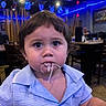 toddler, child, spaghetti, food, restaurant, blue_lighting, indoor, person, curly_hair, shirt, dining, seat, table, face, expression, large_eyes, messy, cute, young, portrait