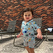 Victor joined the competition — help win amazing prizes! toddler, child, swimsuit, dinosaur_pattern, barefoot, outdoor, sunny, brick_wall, patio, concrete_floor, chair, metal_chair, shadow, expression, person, summer, cute, standing, playful, young_child