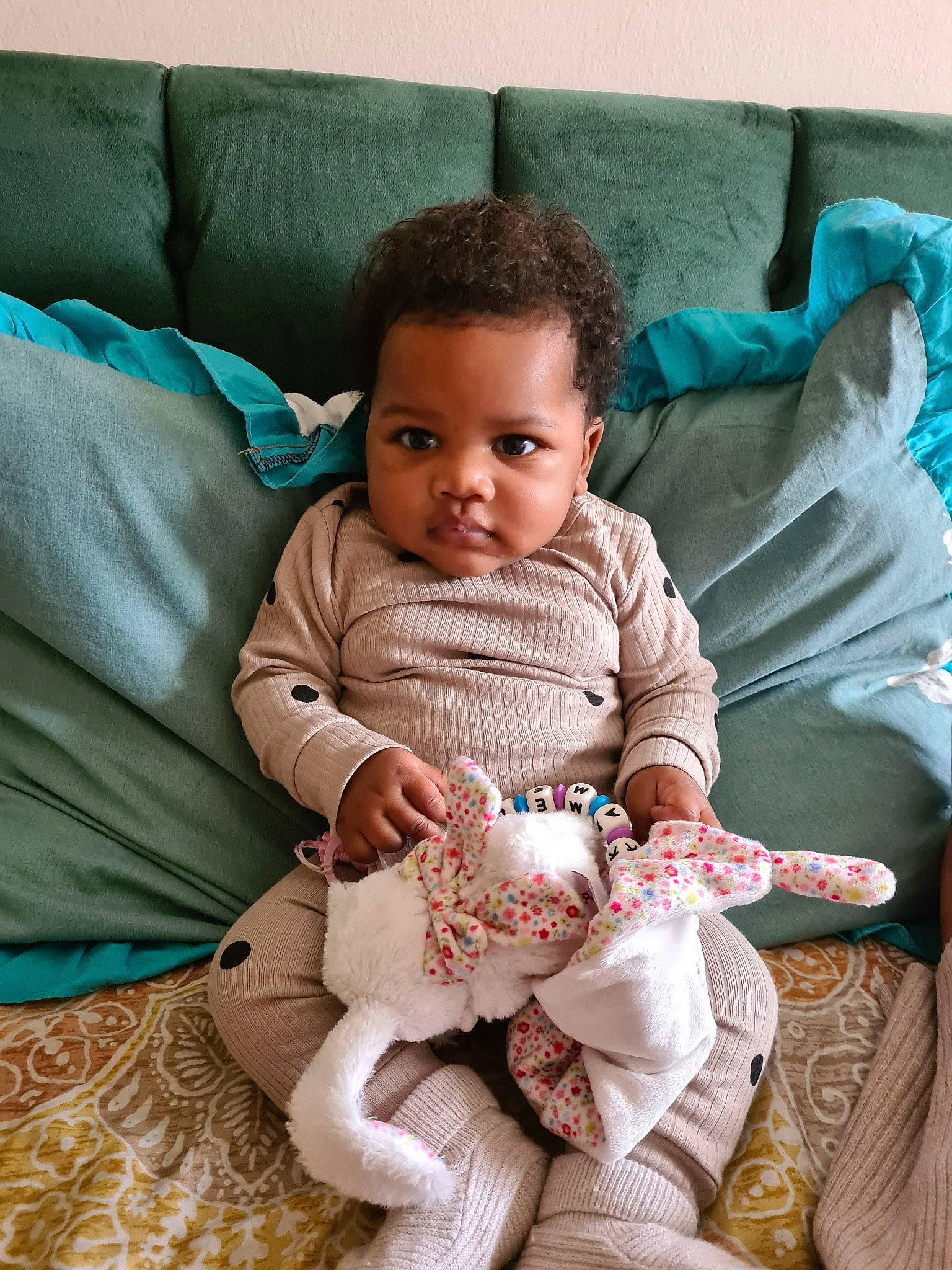 Kamelya participe au concours pour gagner de l'argent avec cette photo : baby, baby_toddler_clothing, child, comfort, couch, eye, face, fur, happy, head, linens, outerwear, pattern, person, room, sitting, sleeve, smile, textile, throw_pillow