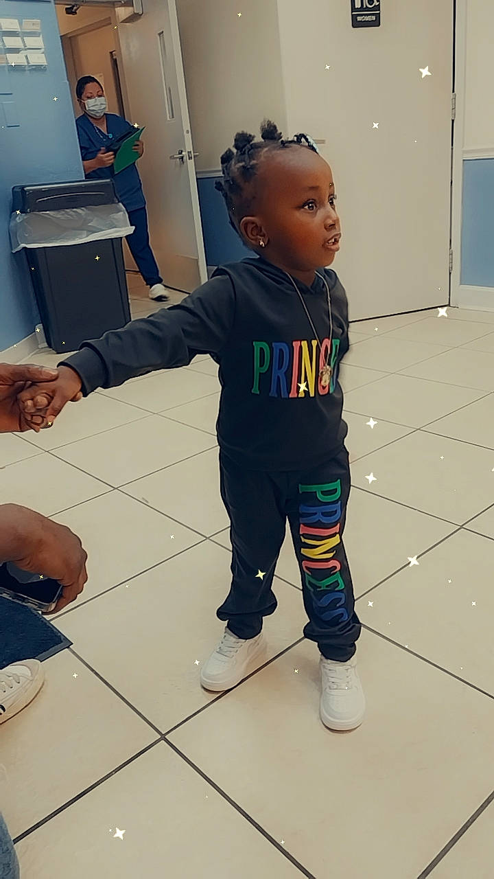 Jhene is registered to the contest to win money with this photo: baby, child, event, fashion_design, fictional_character, floor, flooring, fun, gesture, joint, knee, leg, person, room, sneakers, sportswear, standing, sweatpant, television, thumb