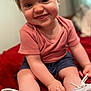 baby, child, clothing, cute, face, hair, happy, human, indoor, navy_shorts, pink_shirt, portrait, red_blanket, shoes, sitting, skin, smile, toddler, white_sneakers, young_child