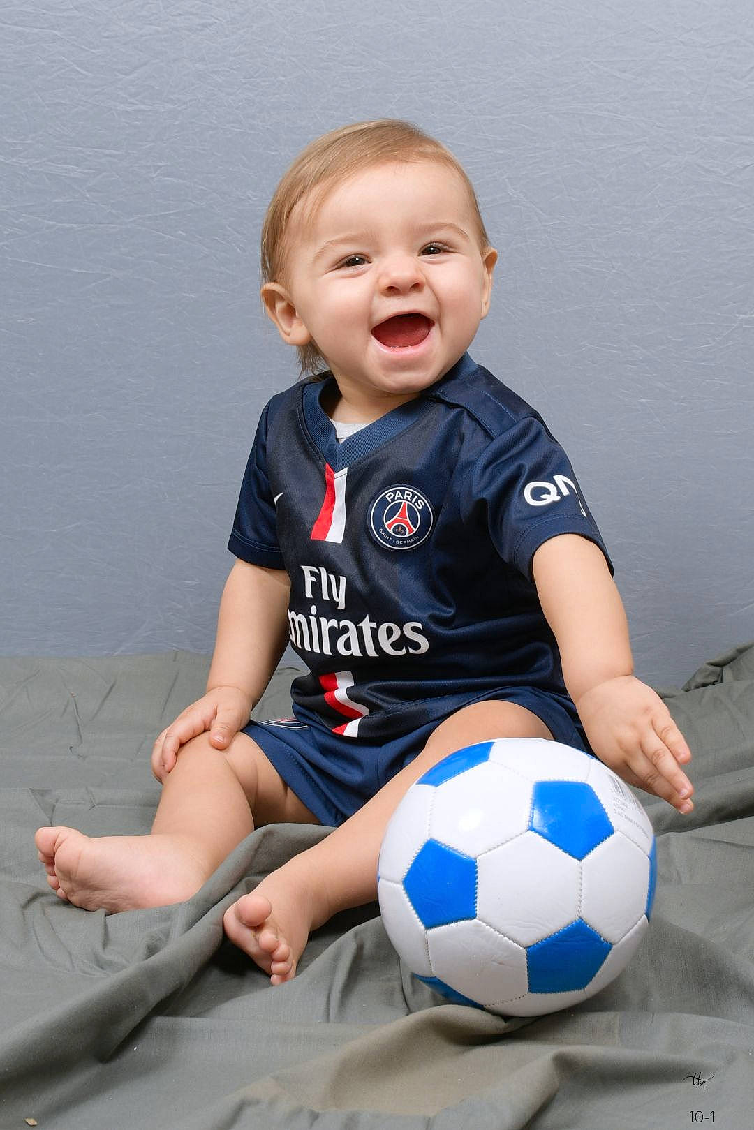 Gaye participe au concours pour gagner de l'argent avec cette photo : baby_toddler_clothing, ball, child, electric_blue, flash_photography, football, fun, happy, human_leg, knee, person, shorts, sitting, sleeve, smile, soccer, soccer_ball, sports_equipment, sportswear, t_shirt