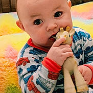 Robert is registered to the contest to win money with this photo: baby, child, toy, giraffe, pajamas, colorful, blanket, fuzzy, cute, indoors, portrait, face, hand, playful, infant, young_child, chewing, happy, cozy, closeup