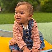 Agathe participe au concours pour gagner de l'argent avec cette photo : baby, child, smiling, denim_overalls, pink_sweater, outdoor, greenery, playground, boat, hands, face, happy, cute, infant, portrait, sitting, nature, daylight, clothing, closeup