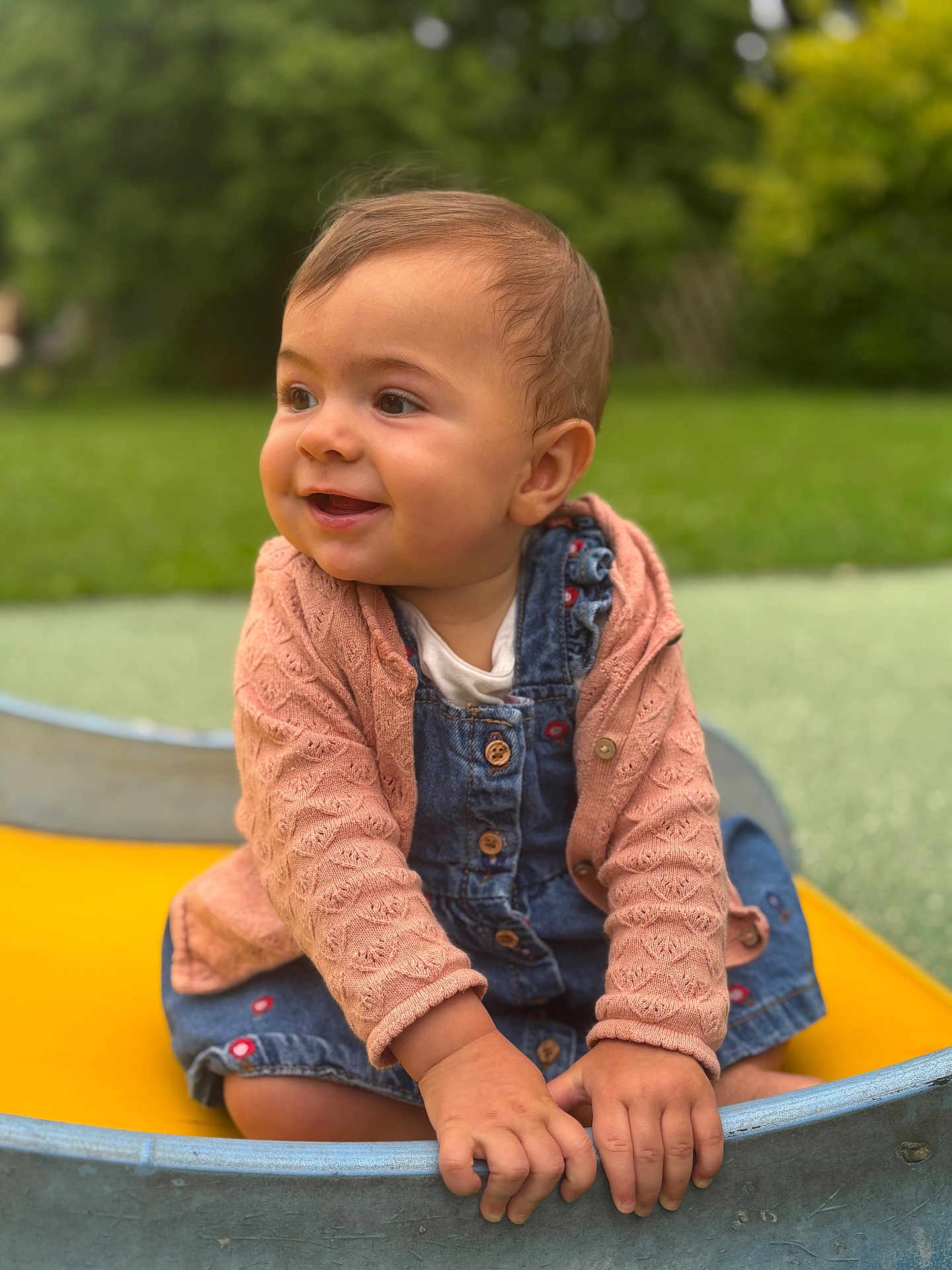 Agathe participe au concours pour gagner de l'argent avec cette photo : baby, child, smiling, denim_overalls, pink_sweater, outdoor, greenery, playground, boat, hands, face, happy, cute, infant, portrait, sitting, nature, daylight, clothing, closeup