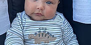 Dylan is registered to the contest to win money with this photo: baby, blue_eyes, car_seat, child, chubby_cheeks, close_up, cute, dinosaur_embroidery, expression, face, hand, human, indoors, infant, onesie, portrait, safety_warning, seated, striped_clothing, young_child