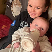 Ezio a rejoint le concours — aidez-le/la à gagner de superbes lots ! child, baby, smile, feeding, bottle, indoors, cute, happy, sibling, clothing, face, portrait, baby_clothes, young, person, holding, seated, blanket, cute_expression, background