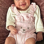 Bella is registered to the contest to win money with this photo: baby, smiling, infant, pink_outfit, bunny_ears, couch, pillows, soft_texture, happy, cute, child, knit_socks, portrait, indoor, young_child, clothing, cozy, face, person, sitting