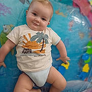 Léo a rejoint le concours — aidez-le/la à gagner de superbes lots ! baby, infant, tshirt, smile, chubby_cheeks, indoor, inflatable_pool, colorful, cute, playful, child, sea_creatures, turtle, fish, palm_tree, sun_graphic, relaxed, skin, legs, happy