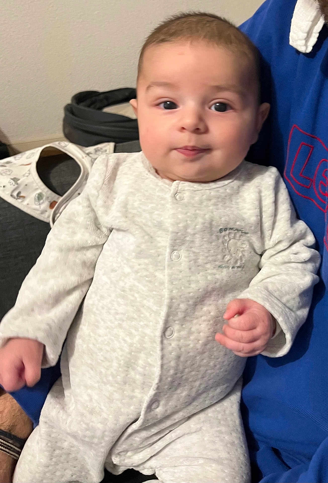 Nolan participe au concours pour gagner de l'argent avec cette photo : baby, infant, onesie, white_clothing, person, indoor, face, hand, sitting, holding, curious, young_child, cute, child, casual, portrait, human, soft_lighting, cozy, closeup