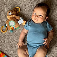 Alfred joined the competition — help win amazing prizes! baby, infant, child, carpet, plush_toy, teddy_bear, blue_onesie, play_mat, floor, indoor, person, cute, chubby_cheeks, laying_down, toy, colorful, soft_toy, young_child, looking_at_camera, calm_expression