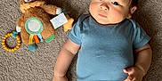 Alfred joined the competition — help win amazing prizes! baby, infant, child, carpet, plush_toy, teddy_bear, blue_onesie, play_mat, floor, indoor, person, cute, chubby_cheeks, laying_down, toy, colorful, soft_toy, young_child, looking_at_camera, calm_expression