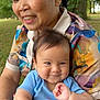 elderly_woman, baby, smiling, outdoor, nature, greenery, trees, colorful_clothing, floral_pattern, embrace, happy, portrait, family, baby_clothes, person, skin, head, face, closeup, love