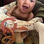 baby, smiling, infant, face, toy, plush_toy, baby_seat, colorful, happy, indoors, child, person, cute, soft_toy, rings, clothing, head, seat, play, joyful