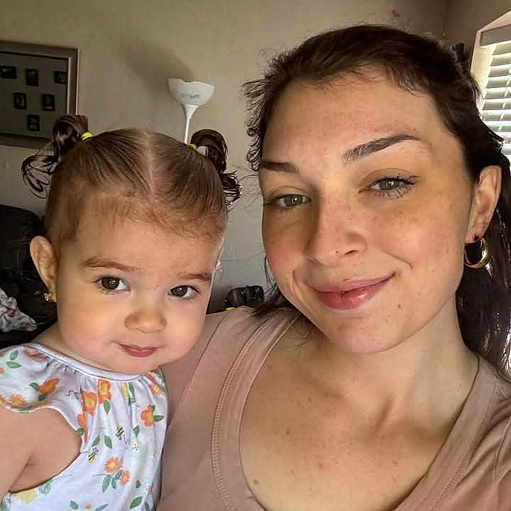 Hailey joined the competition — help win amazing prizes! child, dress, earrings, face, family, floral_pattern, hair, home, indoor, lamp, light, living_room, person, pigtails, portrait, shirt, smile, toddler, window, woman