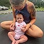 baby, adult, tattoo, outdoor, trampoline, trees, grass, parking_lot, car, onesie, holding, sitting, person, child, nature, casual_clothing, barefoot, curious, love, family