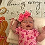 Nylah joined the competition — help win amazing prizes! baby, infant, pink_bow, barbie_outfit, smiling, blanket, soft_towel, headband, child, cute, happy, lying_down, indoors, colorful_background, numbers, flower_pattern, skin, person, toddler, playful