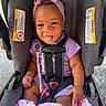 baby, child, car_seat, headband, bow, purple_outfit, pacifier, blanket, pink, smiling, tongue_out, straps, cute, infant, sitting, indoors, playful, happy, person, young