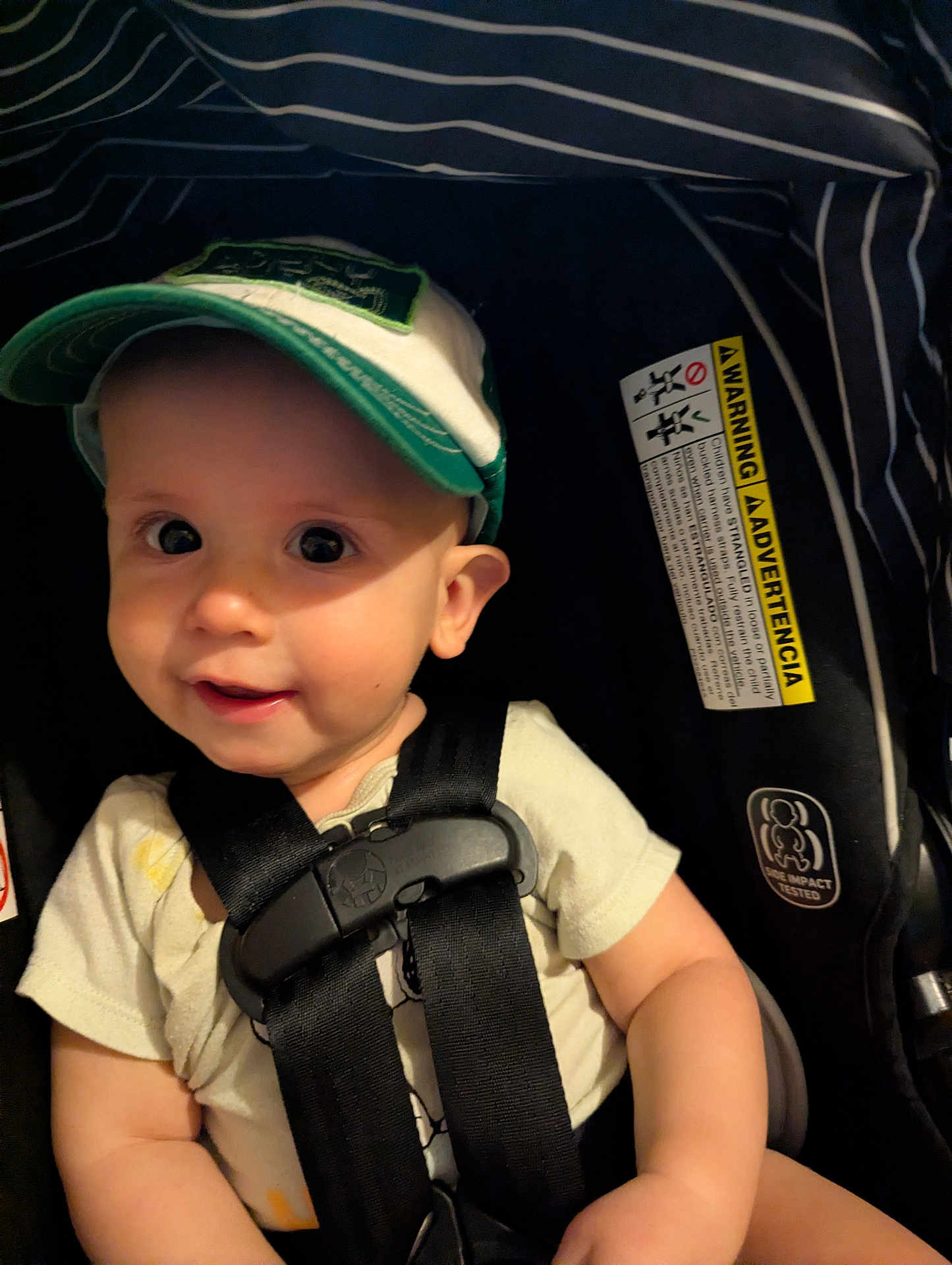 Reese joined the competition — help win amazing prizes! baby, cap, car_seat, child, smile, straps, clothing, infant, seatbelt, warning_label, striped_fabric, cute, safety, young_child, portrait, indoor, headwear, black_straps, happy, closeup