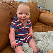 Atlas is registered to the contest to win money with this photo: baby, smile, blue_eyes, striped_clothing, sitting, couch, leather, blanket, indoor, happy, child, infant, person, portrait, cozy, furniture, home, soft, cute, casual