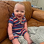 baby, smile, blue_eyes, striped_clothing, sitting, couch, leather, blanket, indoor, happy, child, infant, person, portrait, cozy, furniture, home, soft, cute, casual