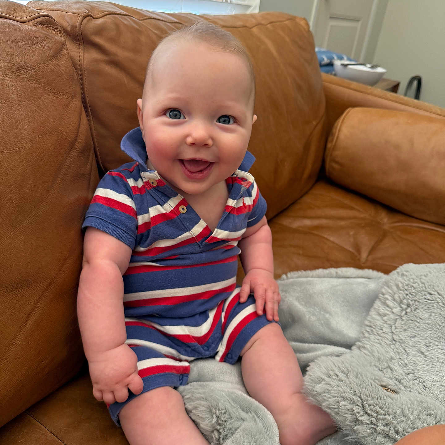 Atlas is registered to the contest to win money with this photo: baby, blanket, blue_eyes, casual, child, couch, cozy, cute, furniture, happy, home, indoor, infant, leather, person, portrait, sitting, smile, soft, striped_clothing