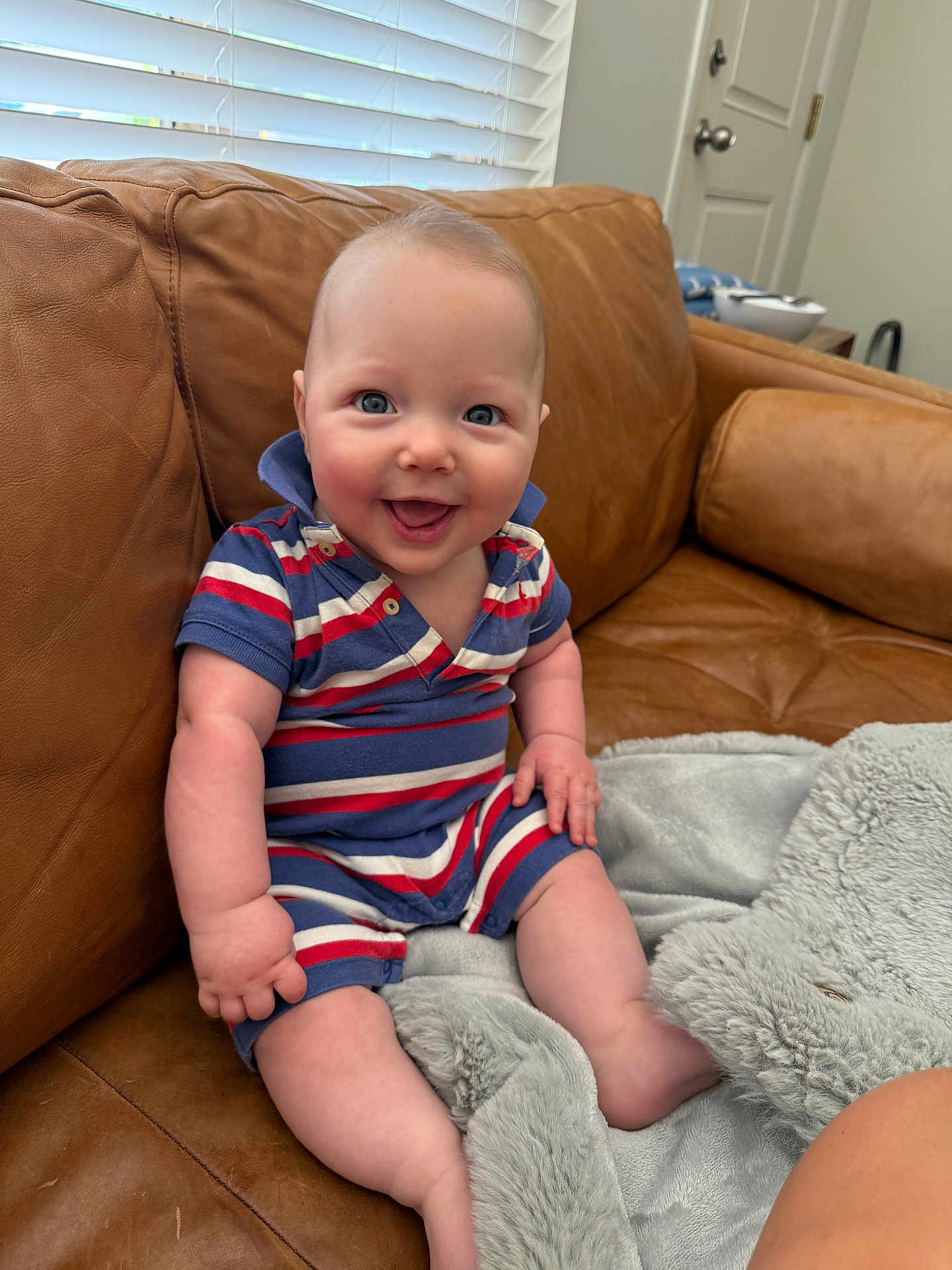 Atlas is registered to the contest to win money with this photo: baby, smile, blue_eyes, striped_clothing, sitting, couch, leather, blanket, indoor, happy, child, infant, person, portrait, cozy, furniture, home, soft, cute, casual