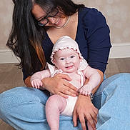 Esmeralda is registered to the contest to win money with this photo: baby, adult, smile, bonnet, glasses, denim, sitting, portrait, indoor, floor, necklace, hand, lap, cuddling, happy, skin, jewelry, woman, infant, studio