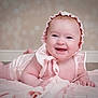 Esmeralda is registered to the contest to win money with this photo: baby, infant, bonnet, smile, laughing, blanket, pink, rosy_cheeks, chubby_cheeks, portrait, studio_photography, lying_down, hands, eyes, earrings, skin, floor, bokeh_background, toy, cute