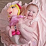 Esmeralda is registered to the contest to win money with this photo: baby, infant, smiling, doll, plush_toy, pink_blanket, bonnet, chubby_cheeks, toes, feet, baby_clothing, soft_toy, happy, portrait, indoor, nursery, hardwood_floor, toy_shoes, playful, closeup