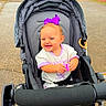 Ella-Grey is registered to the contest to win money with this photo: baby, stroller, child, smiling, outdoor, toy, pathway, grass, footwear, purple_bow, clothing, happy, person, seat, sunny, daytime, cute, infant, playful, park