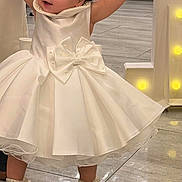 Sakina is registered to the contest to win money with this photo: toddler, child, white_dress, bow, headband, pearl, shoes, floor, tile, indoor, holding_hands, person, baby, celebration, party, cute, smiling, walking, fashion, accessories