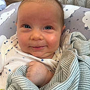 Thaddeus is registered to the contest to win money with this photo: baby, smile, face, infant, blanket, clothing, hand, pillow, pattern, striped, clouds, indoor, cute, child, newborn, portrait, skin, expression, happy, closeup