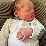 Elyam participe au concours pour gagner de l'argent avec cette photo : newborn, baby, sleeping, infant, cushion, clothing, white_outfit, blue_accent, hand, face, peaceful, soft_texture, indoors, cute, portrait, resting, child, young, cozy, closeup