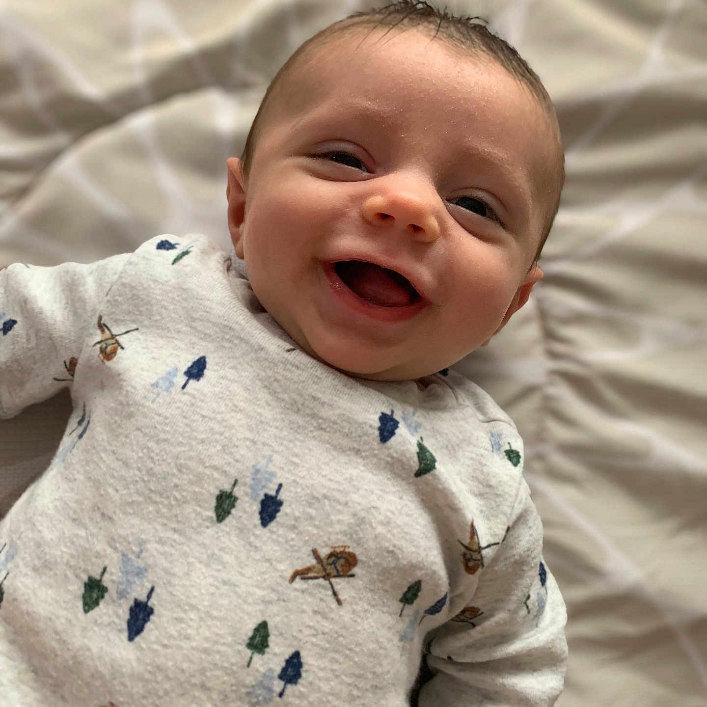 Lukyan is registered to the contest to win money with this photo: baby, blanket, child, closeup, cozy, cute, expression, face, happy, indoors, infant, lying_down, patterned_clothing, person, portrait, smiling, soft_texture, sweater, warm_lighting, young_child