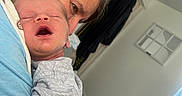Weston joined the competition — help win amazing prizes! baby, sleeping, adult, holding, indoor, window, person, closeup, tender, care, resting, face, human, clothing, light, warmth, skin, portrait, expression, comfort