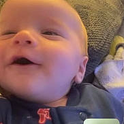 Weston joined the competition — help win amazing prizes! baby, infant, face, smiling, pajamas, couch, blanket, indoor, video_call, person, child, happy, head, cozy, home, communication, technology, portrait, expression, relaxation