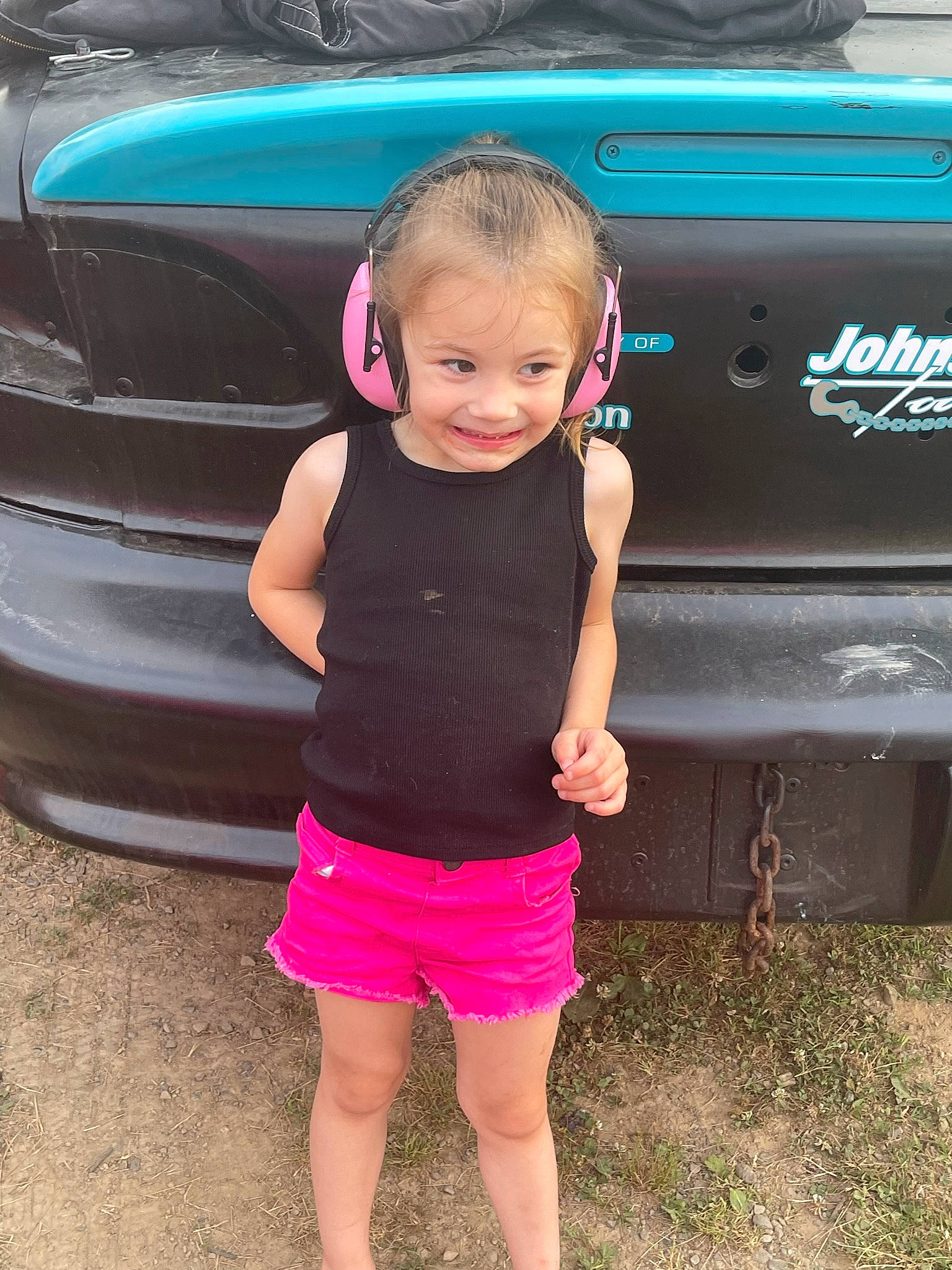 Khloe is registered to the contest to win money with this photo: automotive_design, automotive_exterior, automotive_lighting, automotive_tire, automotive_wheel_system, bumper, car, fender, grass, grille, hood, joy, land_vehicle, motor_vehicle, person, pink, shorts, smile, trunk, vehicle