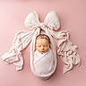 newborn, baby, sleeping, wrapped, cloth, pink_background, bow, headband, flower, soft_texture, portrait, studio, cute, peaceful, infant, child, tender, delicate, lying_down, adorable